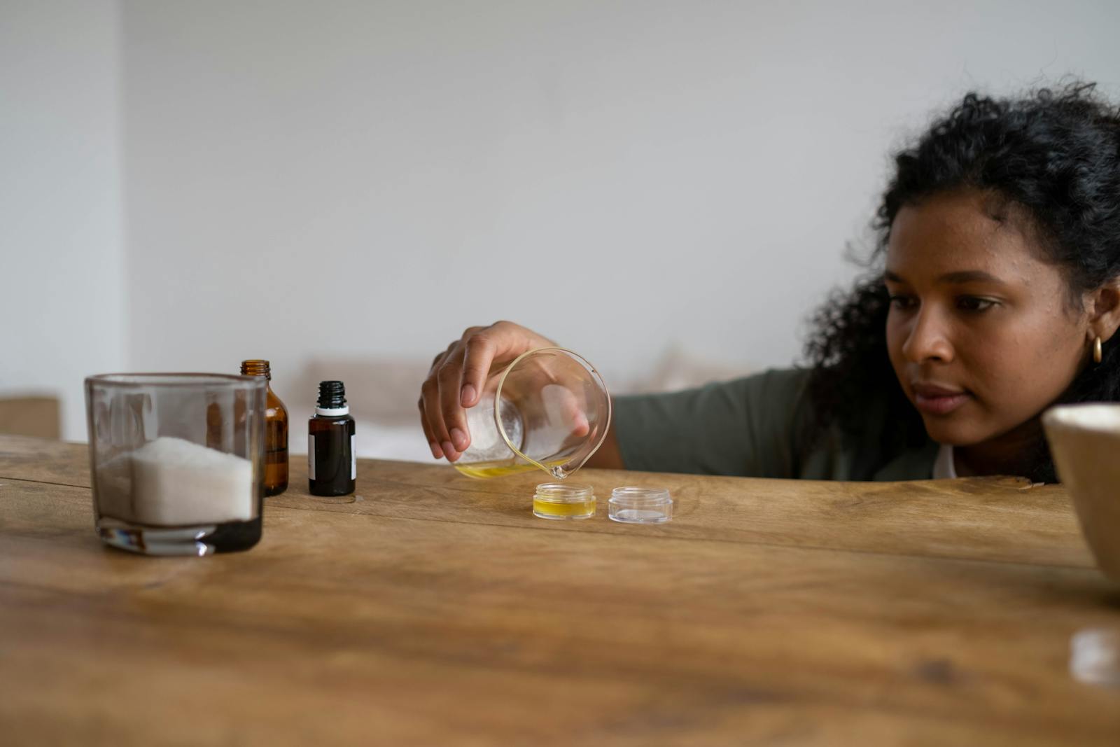 Pot de baume traditionnel ouvert posé sur fond bois clair, texture jaune ambrée