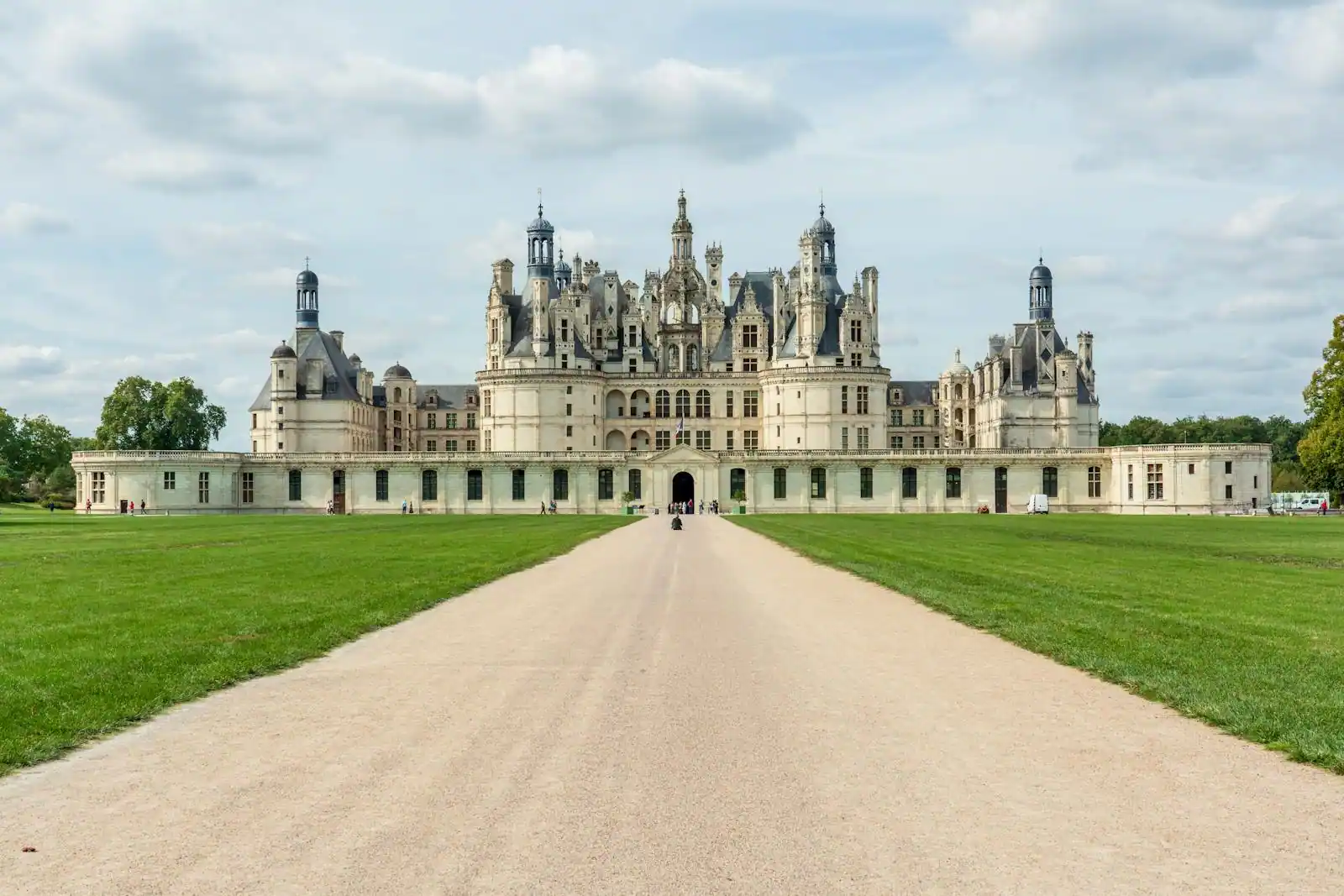 Château de Chambord photographié en fin de journée, tourelles Renaissance se détachant dans une lumière dorée, parc environnant visible au premier plan.