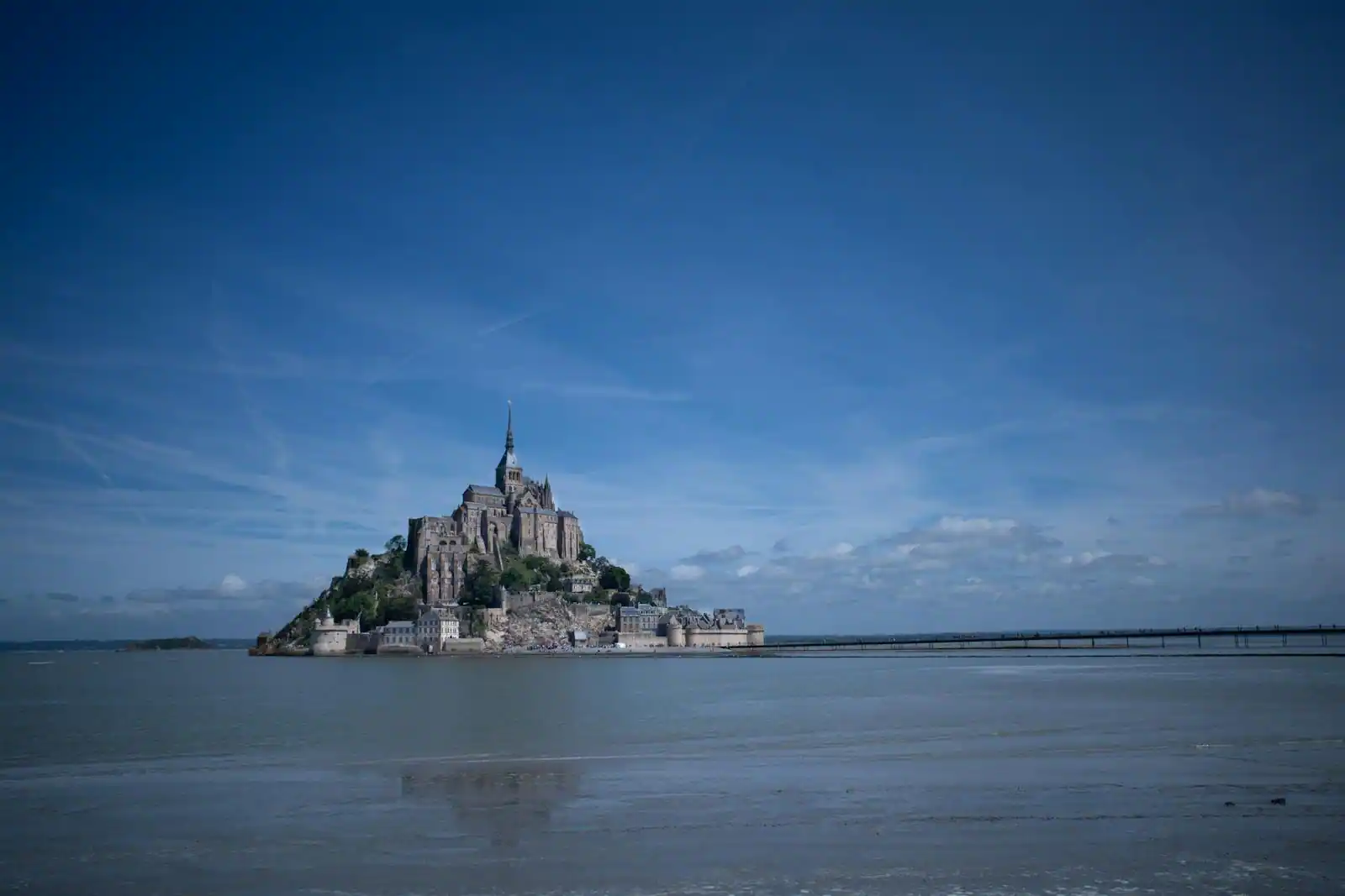 Mont-Saint-Michel et sa baie photographiés en lumière rasante, abbaye sur son rocher, sable à marée basse au premier plan.