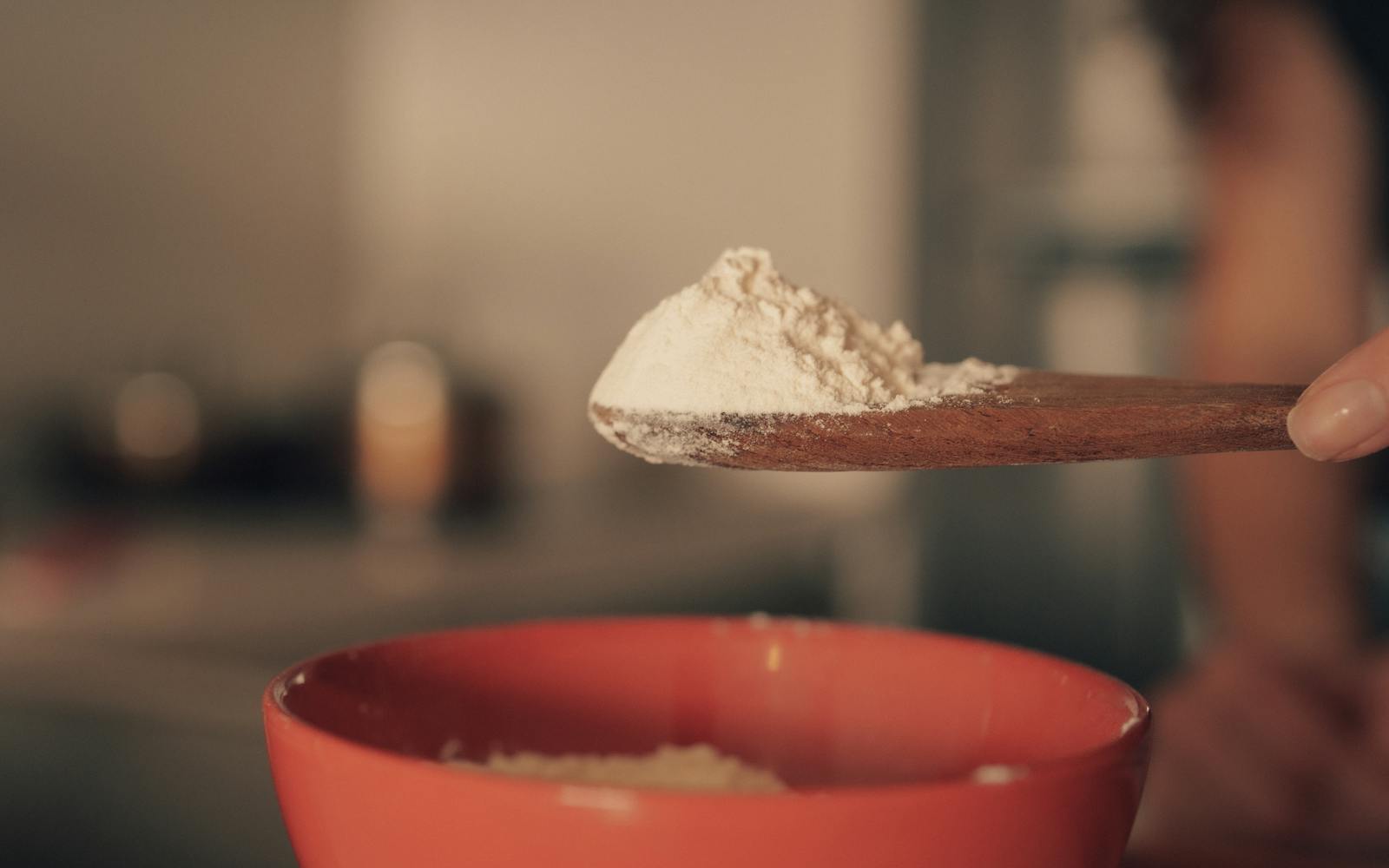 Bocal en verre de bicarbonate de soude avec cuillère en bois sur plan de travail clair, ambiance cuisine naturelle