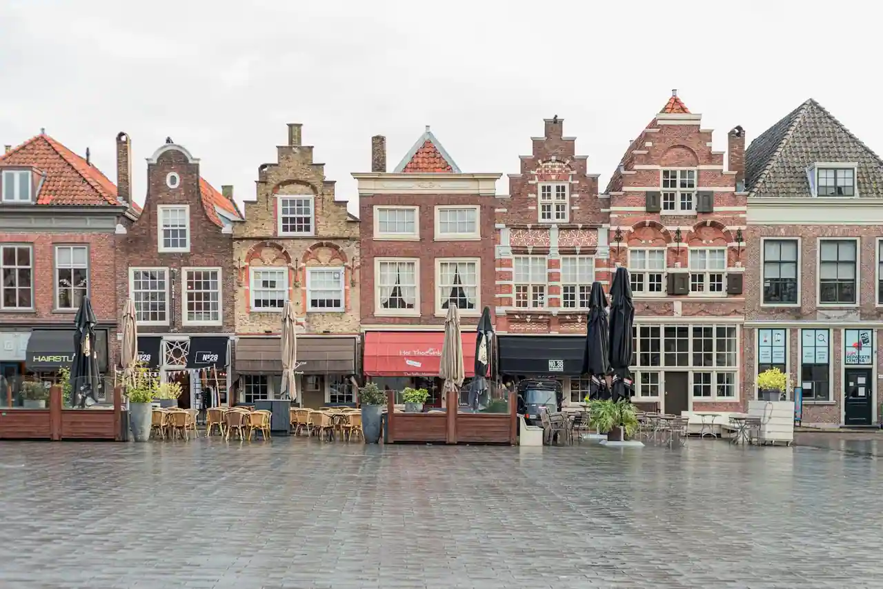 Place européenne pavée au crépuscule, façades anciennes et terrasses de café éclairées.