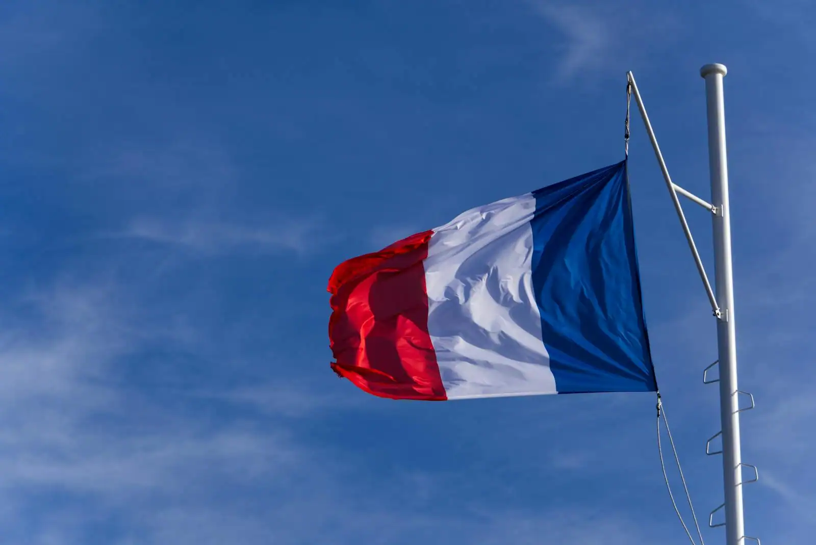 Drapeau tricolore français bleu blanc rouge flottant devant un bâtiment officiel