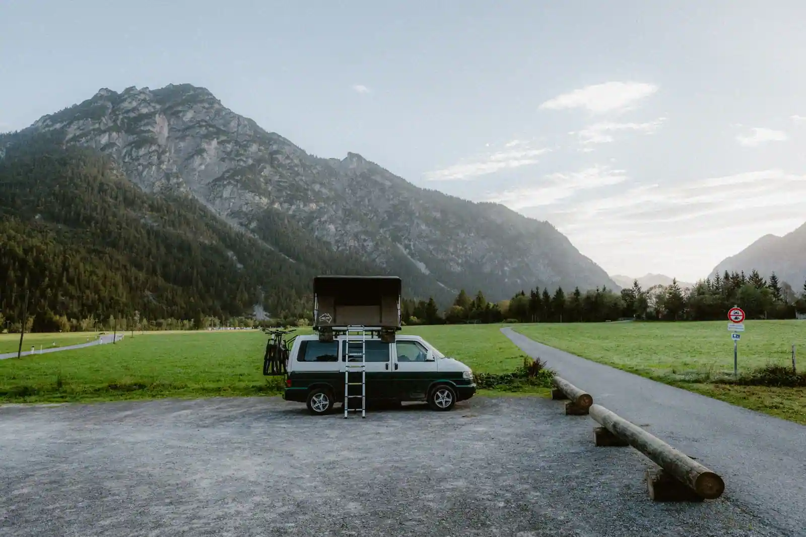 Camping-car stationné sur une aire panoramique en France au lever du jour avec montagnes et brume légère