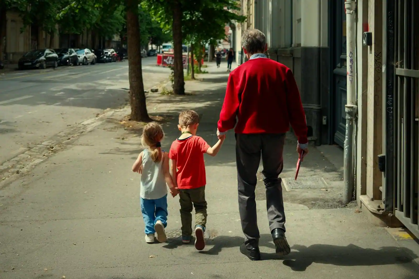 Une famille avec deux enfants marche avec ses valises dans une rue d'une ville européenne ensoleillée