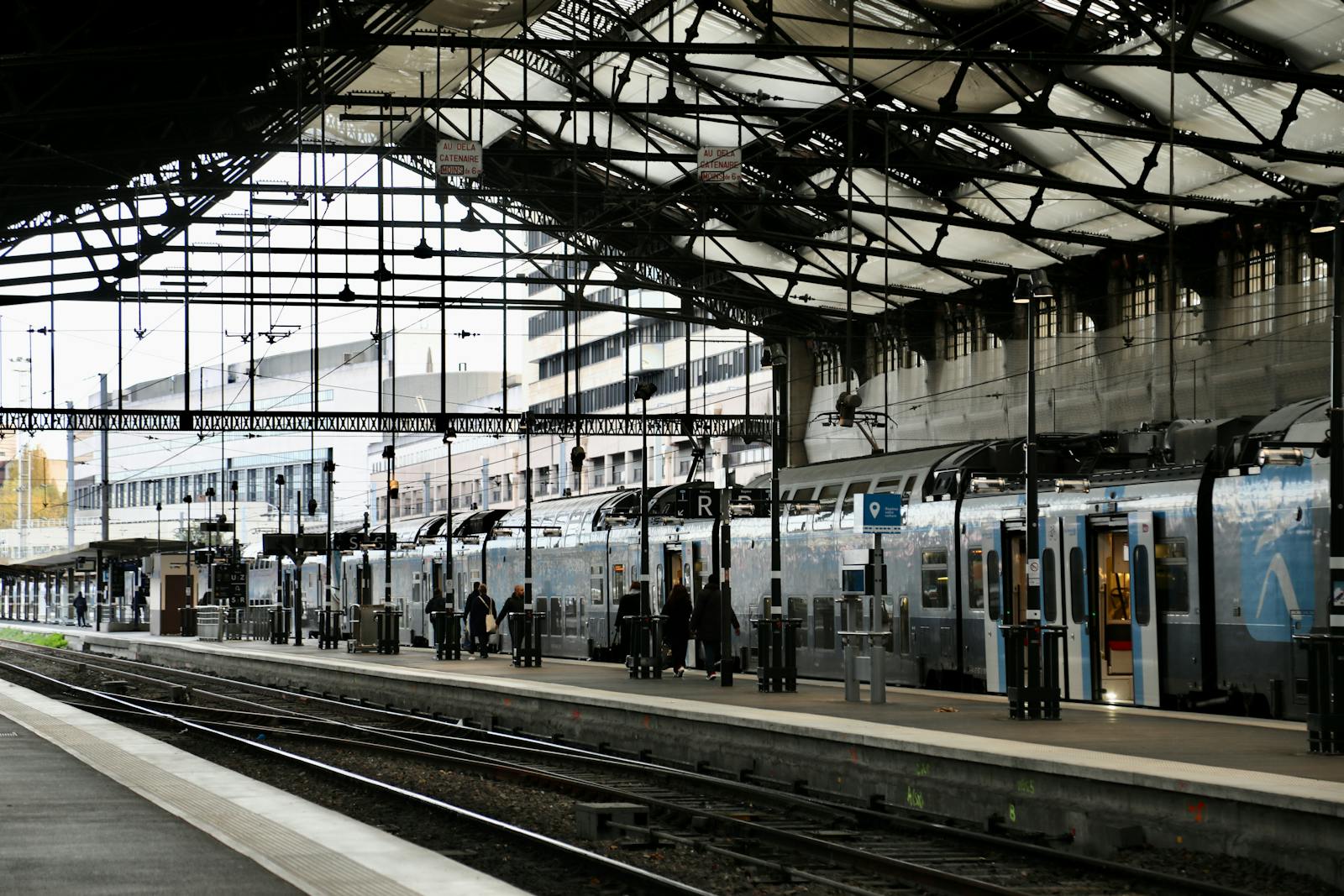 Quai de gare RER moderne avec train arrivant, perspective vers les tours de bureaux