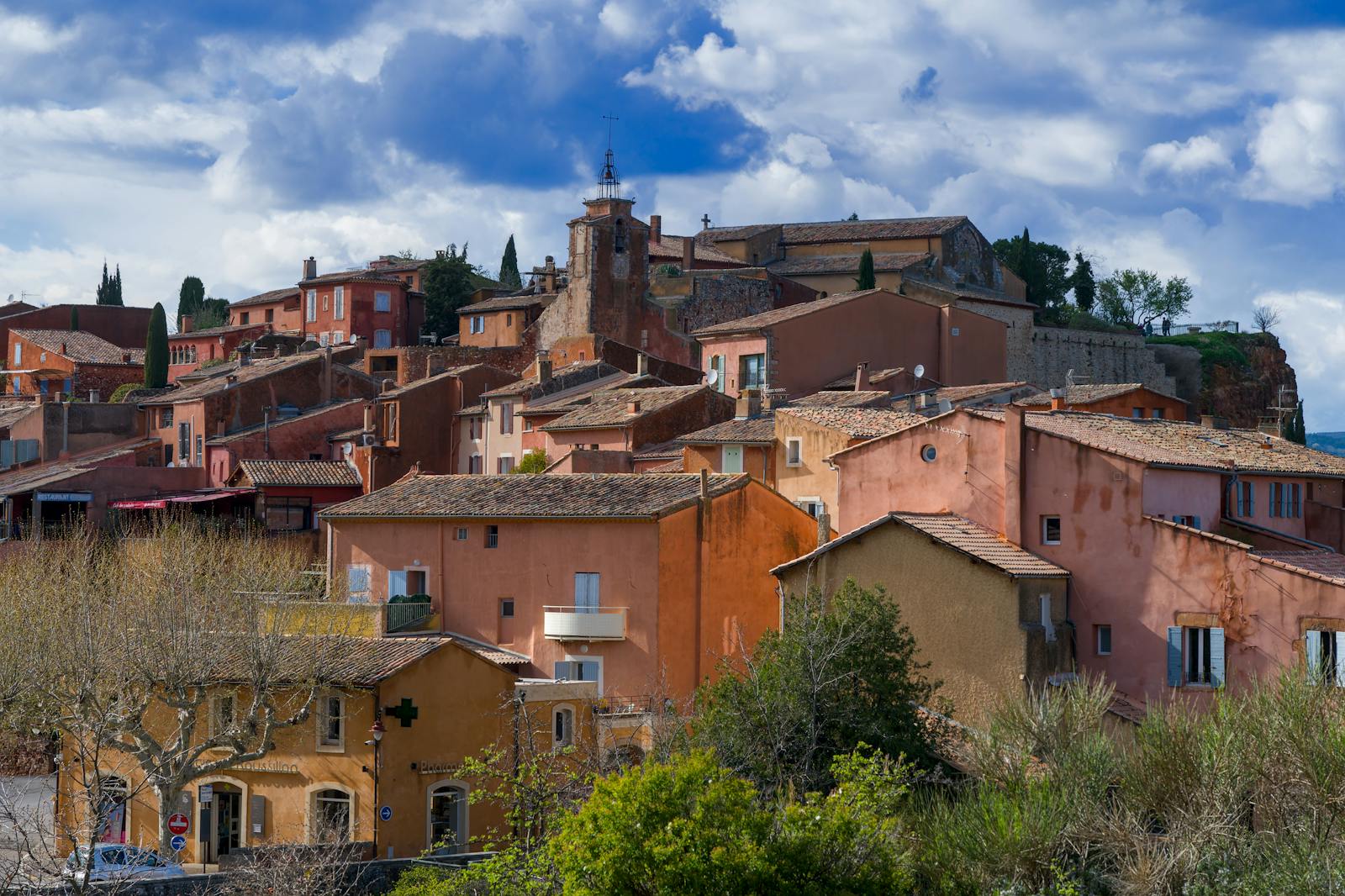 Falaises ocre rouge et jaune du village de Roussillon dans le Luberon, contraste avec les pins méditerranéens