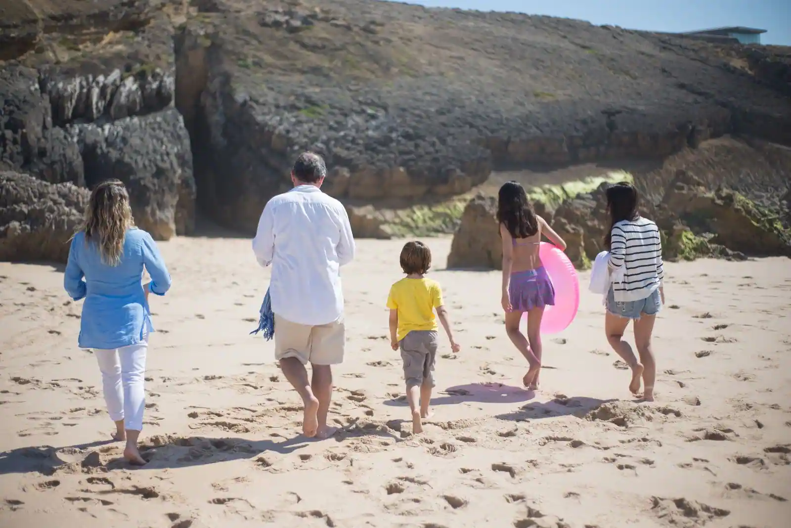 Une famille avec deux enfants marche sur une plage de sable en vacances d'été au bord de la mer
