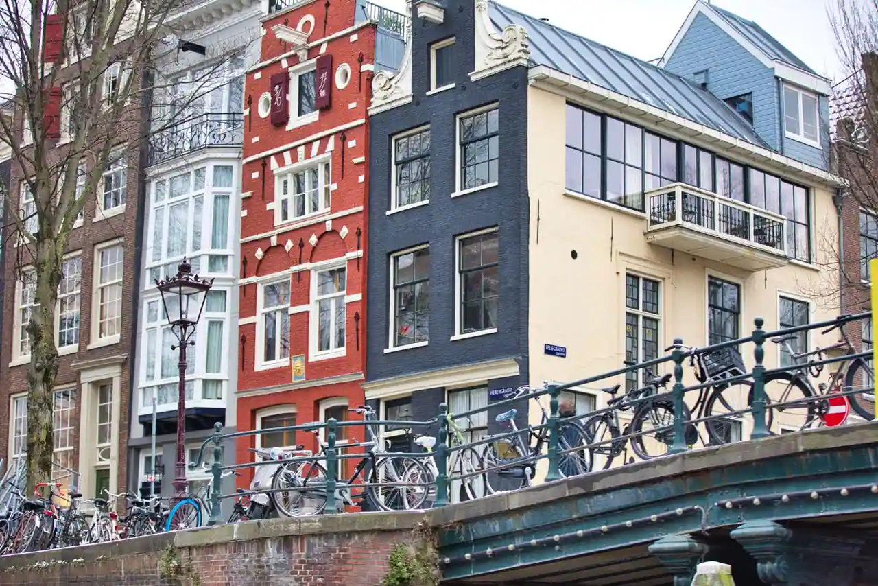 Maisons étroites en brique alignées le long d'un canal d'Amsterdam, vélos garés sur le quai