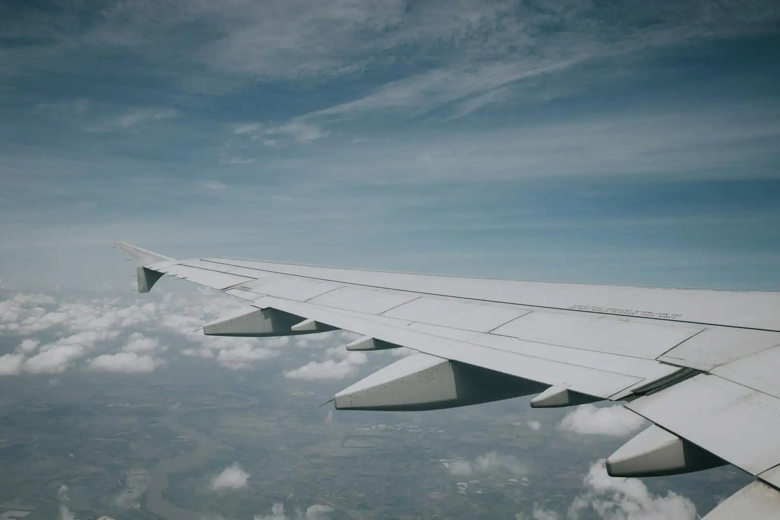 Vue depuis un hublot d'avion sur l'aile et une mer de nuages au-dessus d'un ciel bleu