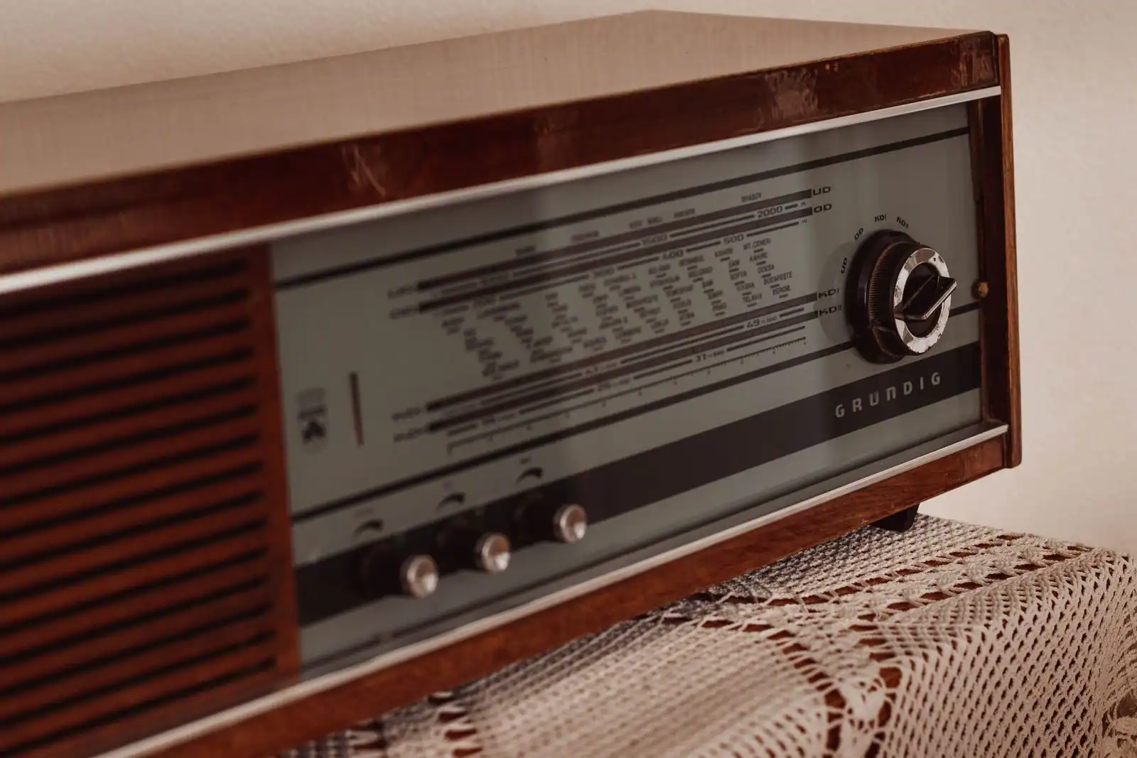 Poste de radio vintage en bois posé sur un napperon en dentelle dans un intérieur clair