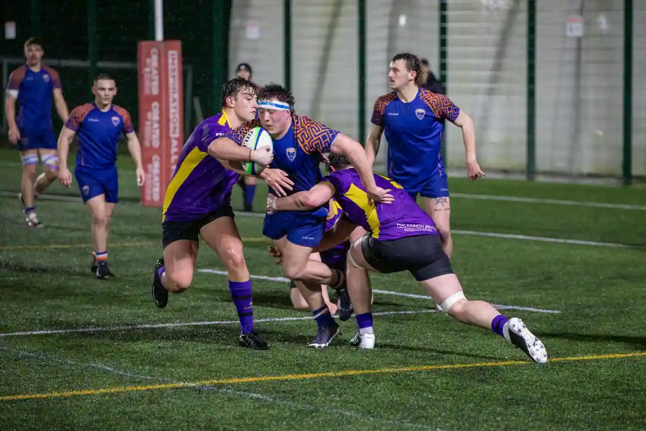 Joueurs de rugby à XV disputant le ballon sur la pelouse d'un stade pendant un match