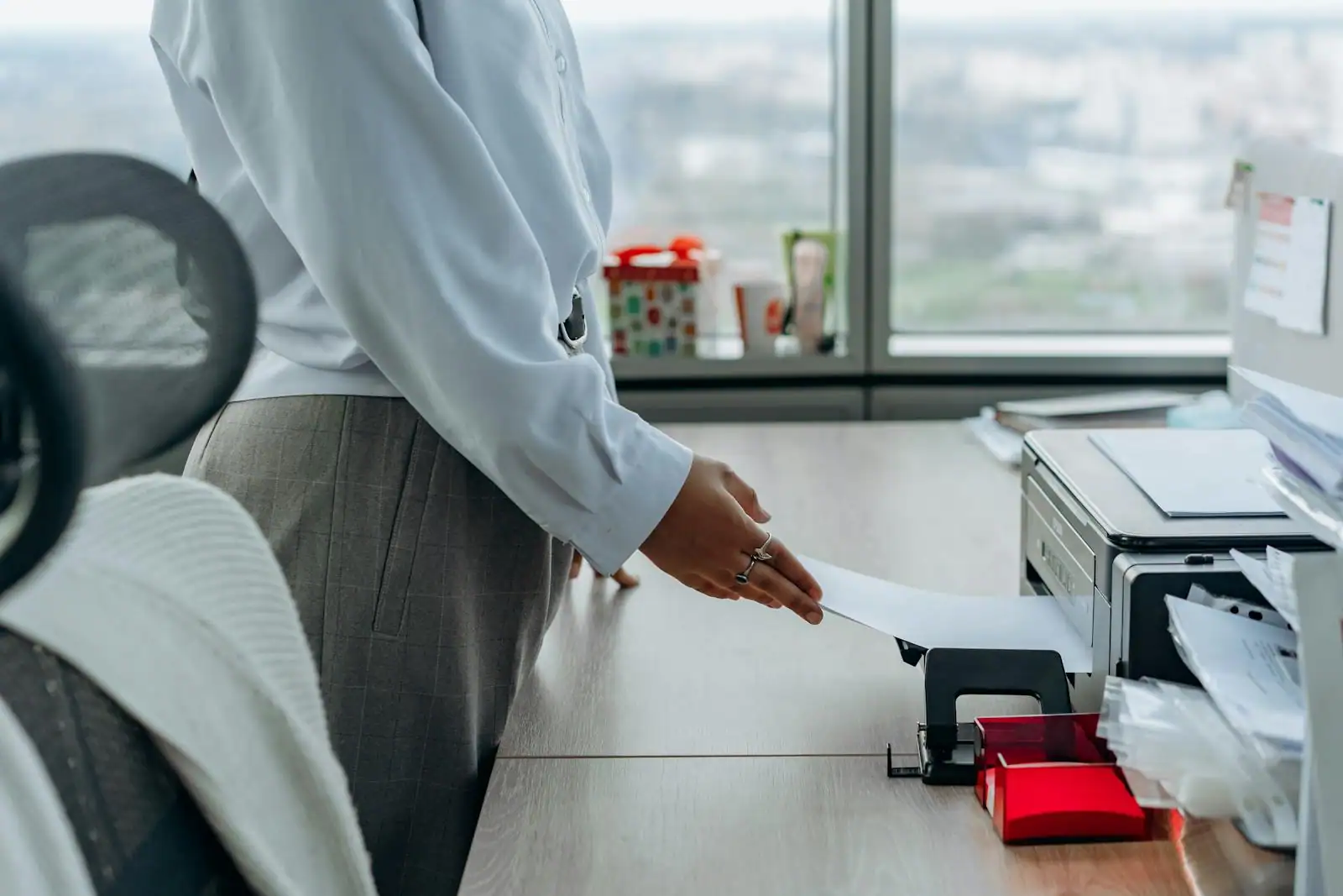 Au bureau, une personne récupère une feuille de papier à côté d'une imprimante posée sur le plan de travail