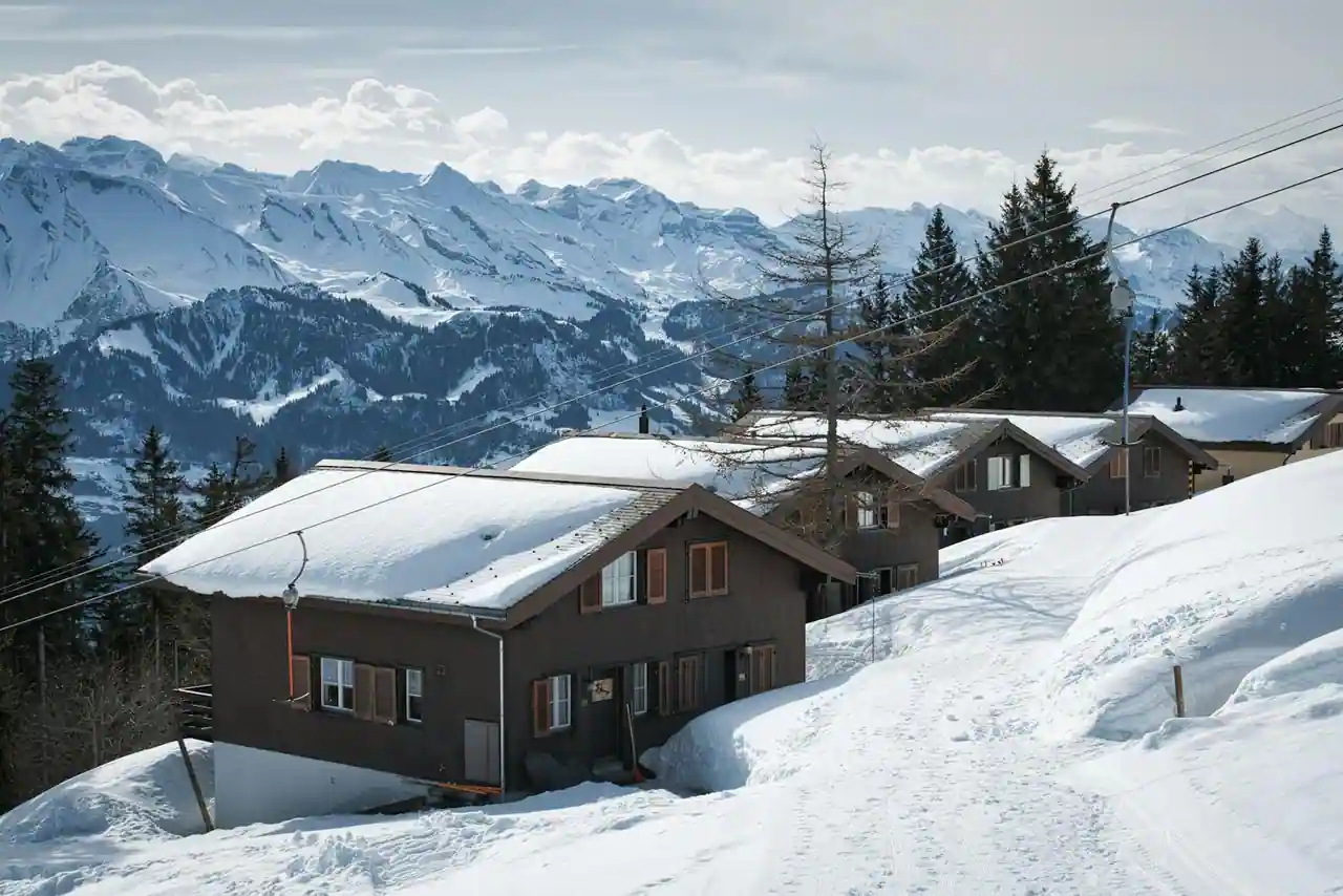 Chalets en bois de montagne sous la neige, sommets enneigés des Alpes en arrière-plan