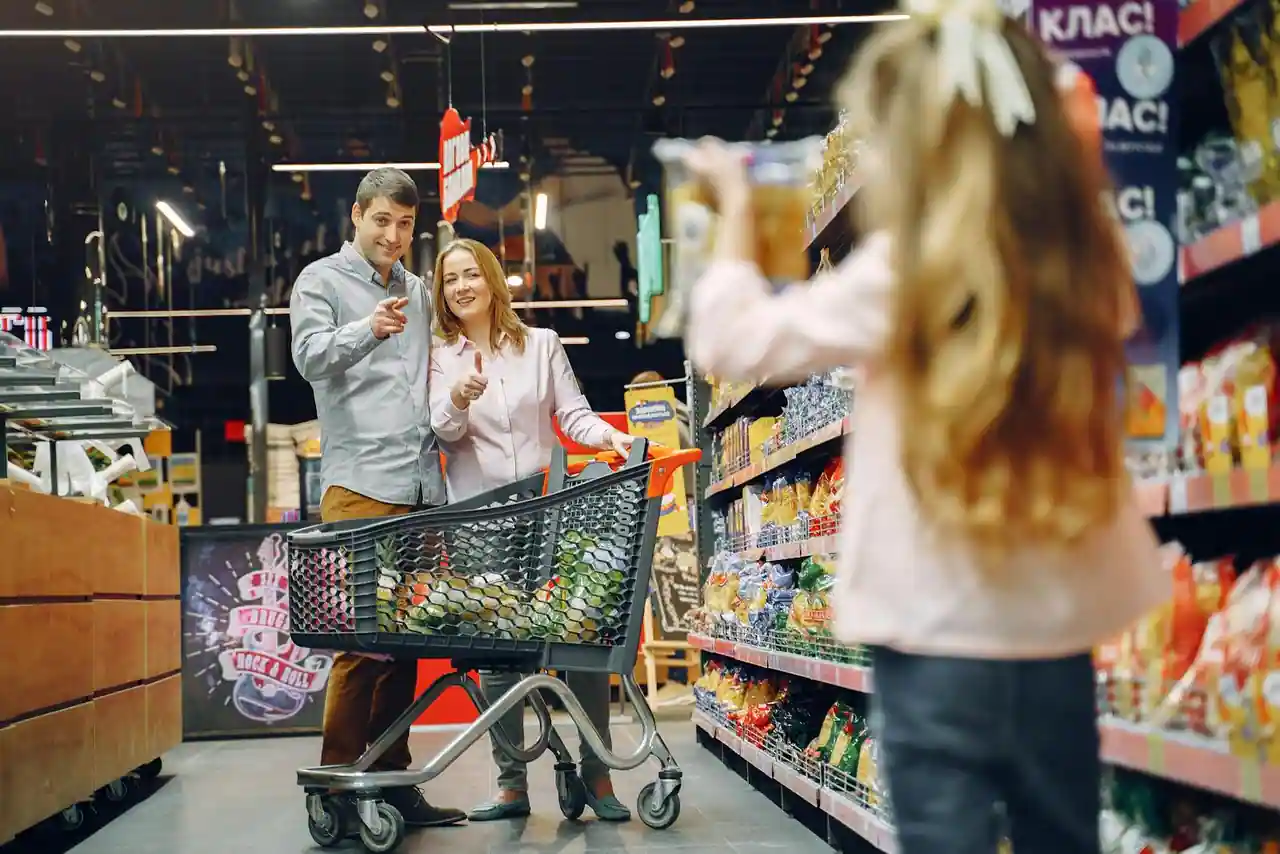 Chariot de courses devant des rayons de supermarché avec étiquettes de prix