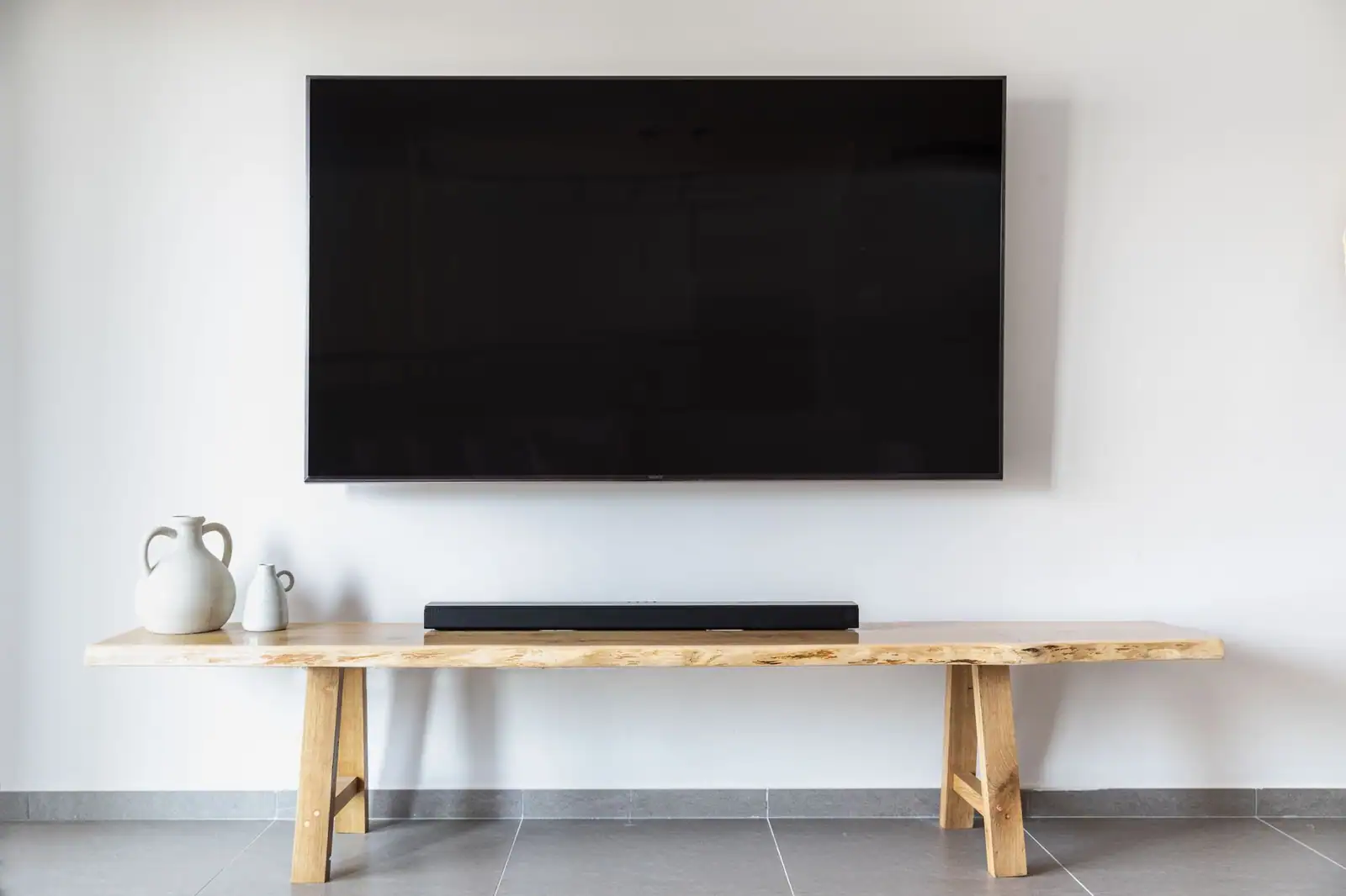Téléviseur à écran plat moderne fixé au mur d'un salon au-dessus d'un meuble en bois