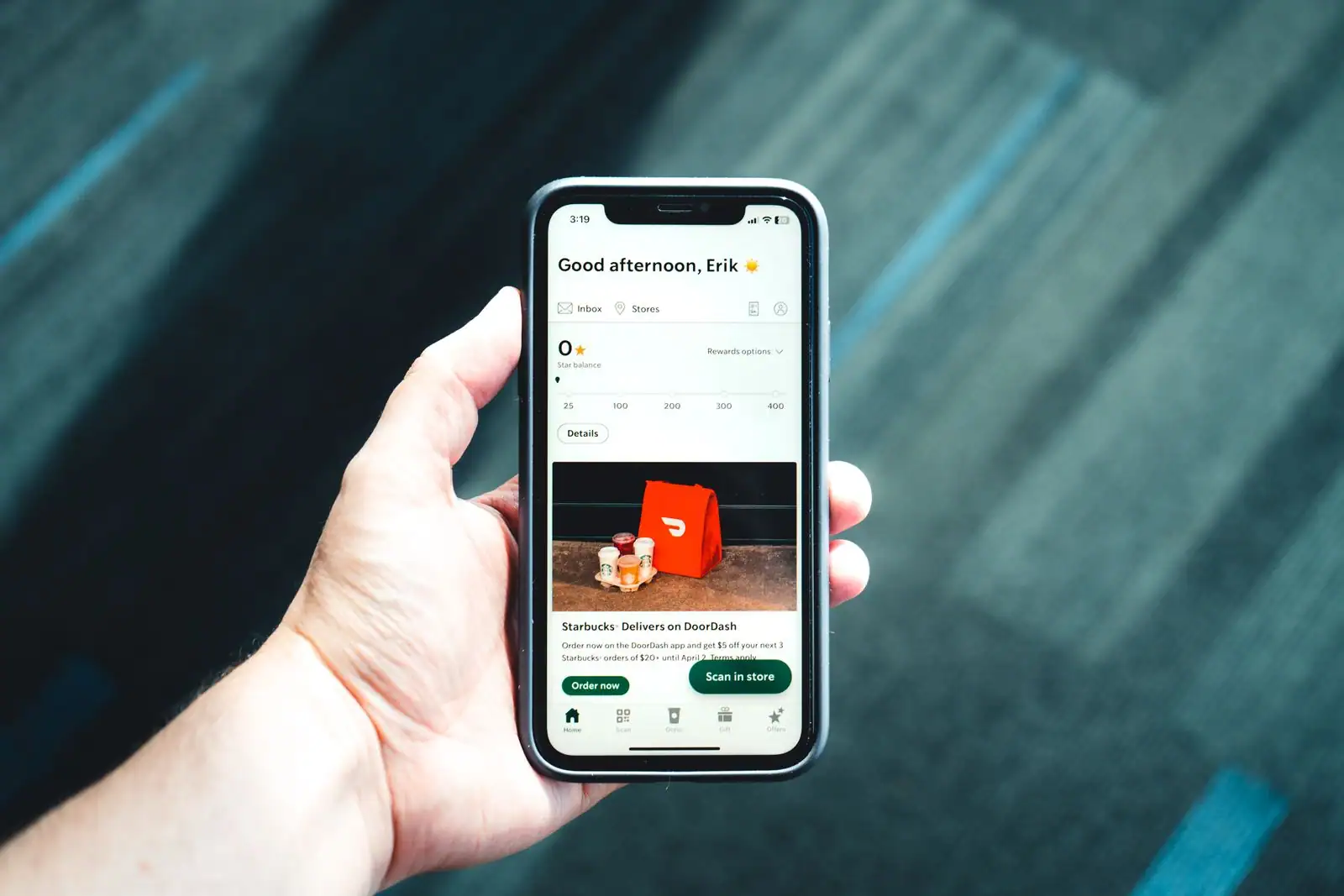 Une main tient un smartphone affichant une application de livraison de repas avec une offre promotionnelle.