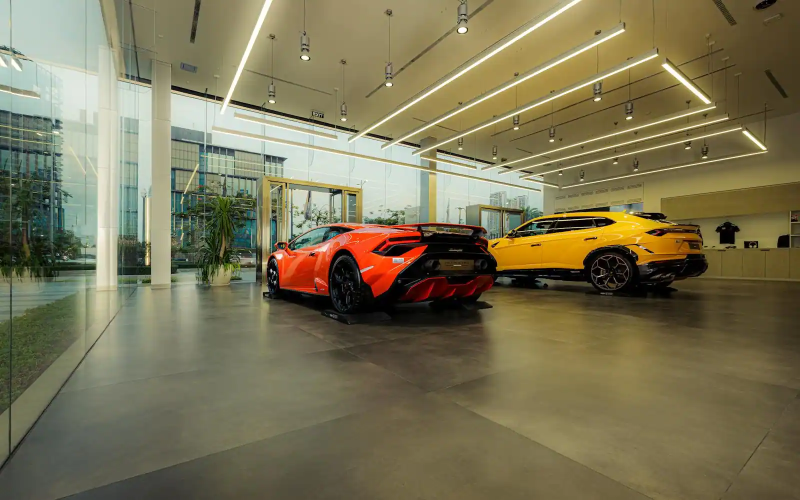 Deux voitures haut de gamme exposées dans le hall vitré d'une concession automobile