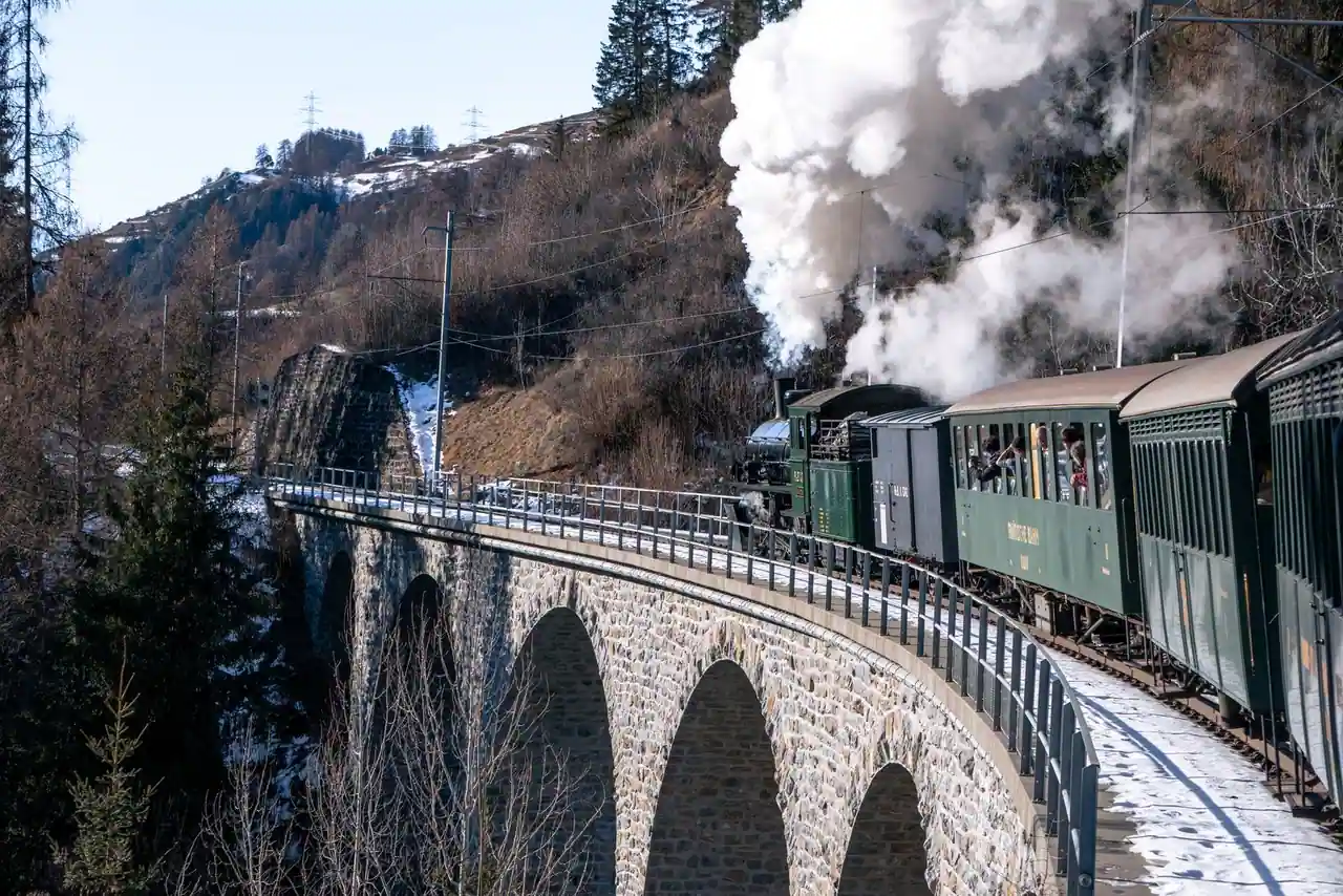 Petit train à voie étroite longeant un paysage de montagne en Corse, illustrant le réseau ferré insulaire.