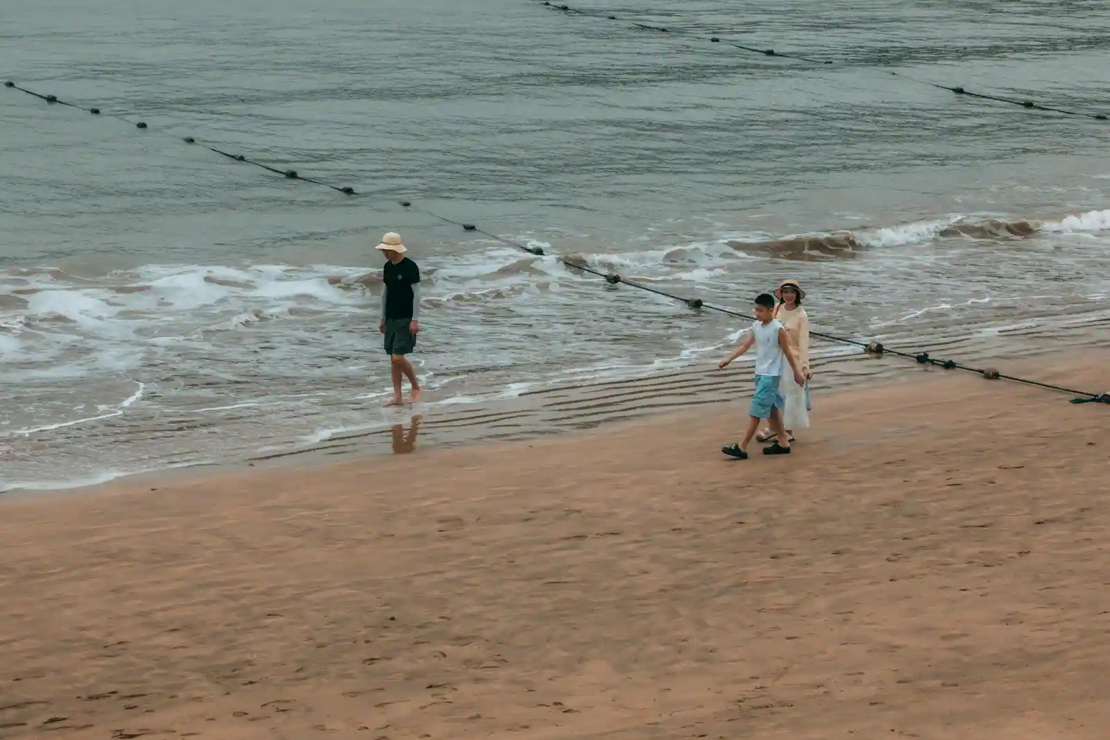 Famille avec enfants marchant sur une grande plage de sable au bord de la mer