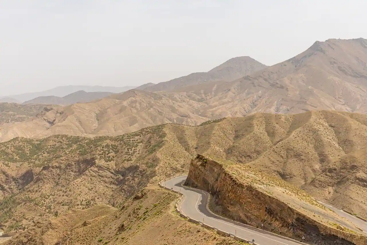 Route de montagne sinueuse traversant les reliefs arides de l'Atlas, au Maroc