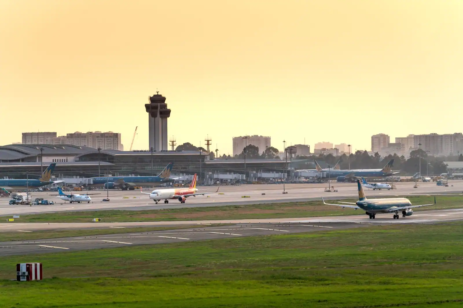 Avions de ligne sur le tarmac d'un aéroport au coucher du soleil, tour de contrôle en arrière-plan.
