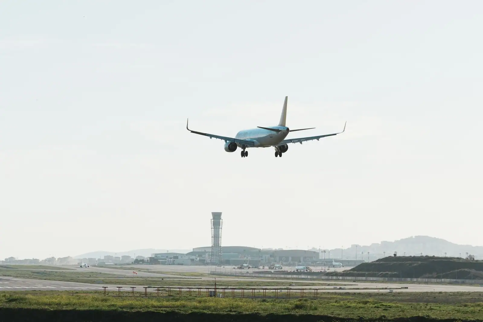 Avion de ligne commercial en approche au-dessus d'un aéroport, train d'atterrissage sorti