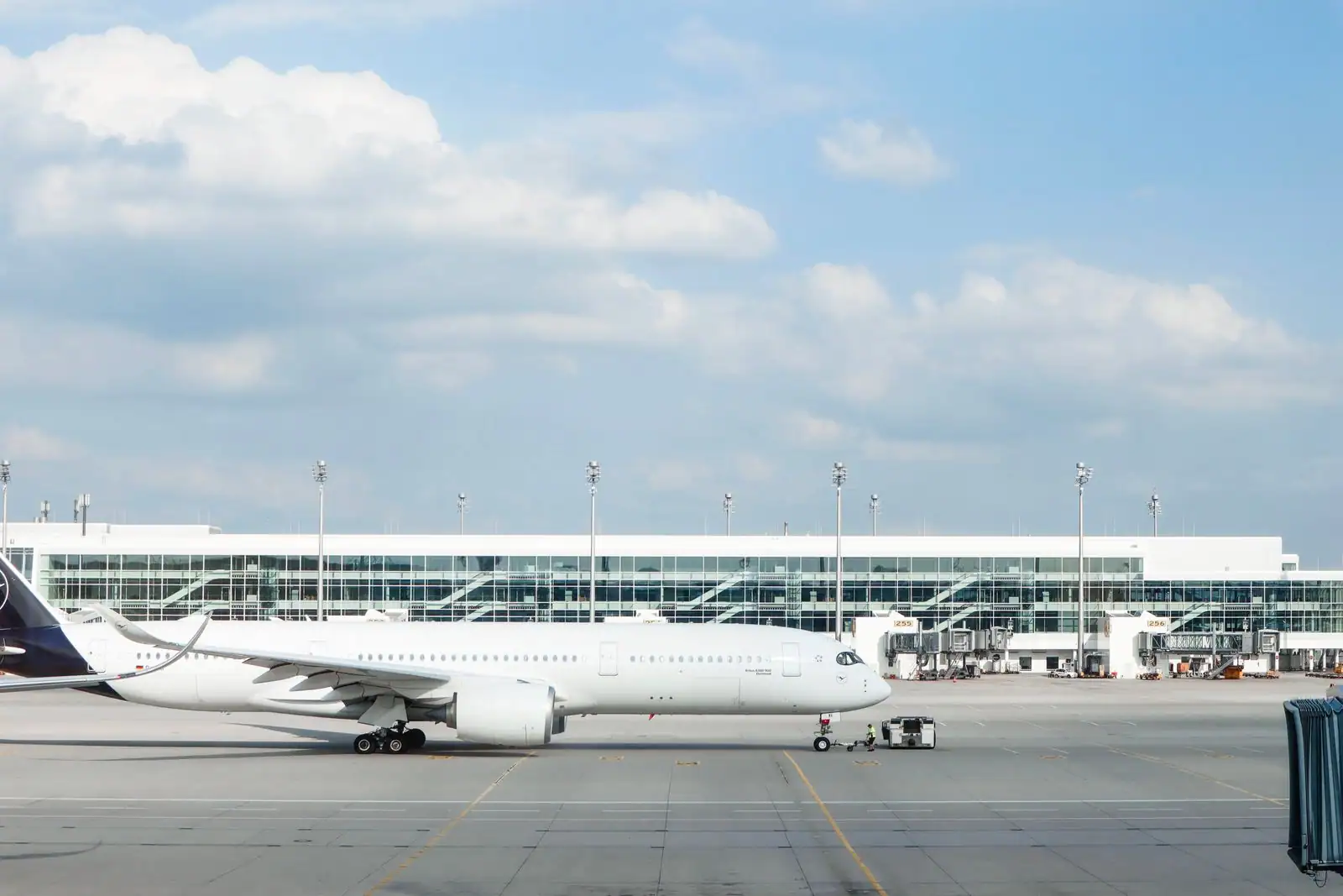 Avion de ligne blanc stationné sur le tarmac devant un terminal d'aéroport, sous un ciel bleu.