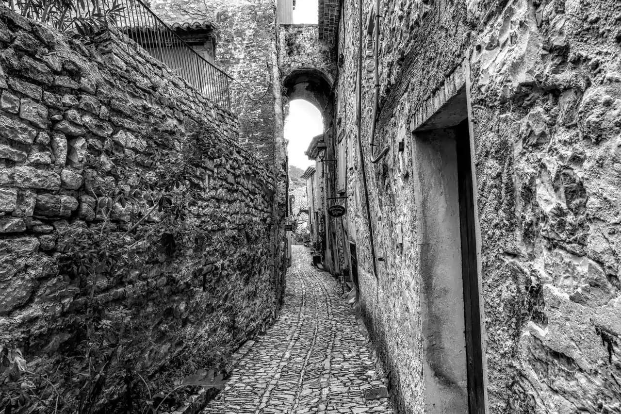Ruelle pavée étroite bordée de vieilles façades en pierre dans un village français au patrimoine préservé