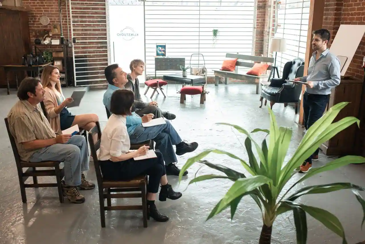 Groupe d'adultes assis prenant des notes pendant une session de formation animée par un intervenant