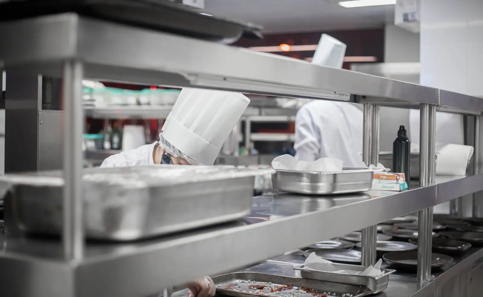 Cuisine de restaurant professionnelle : bacs en inox et étagères de dressage en plein service.
