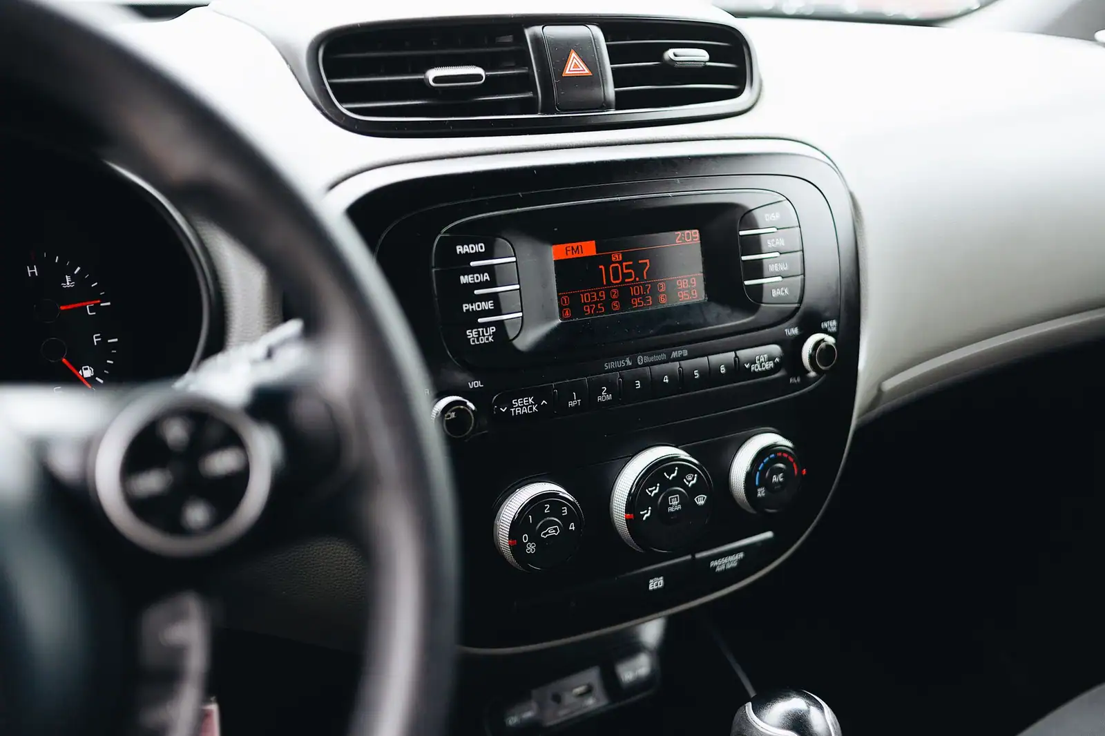 Autoradio allumé affichant une fréquence FM et ses présélections, sur la console centrale d'une voiture