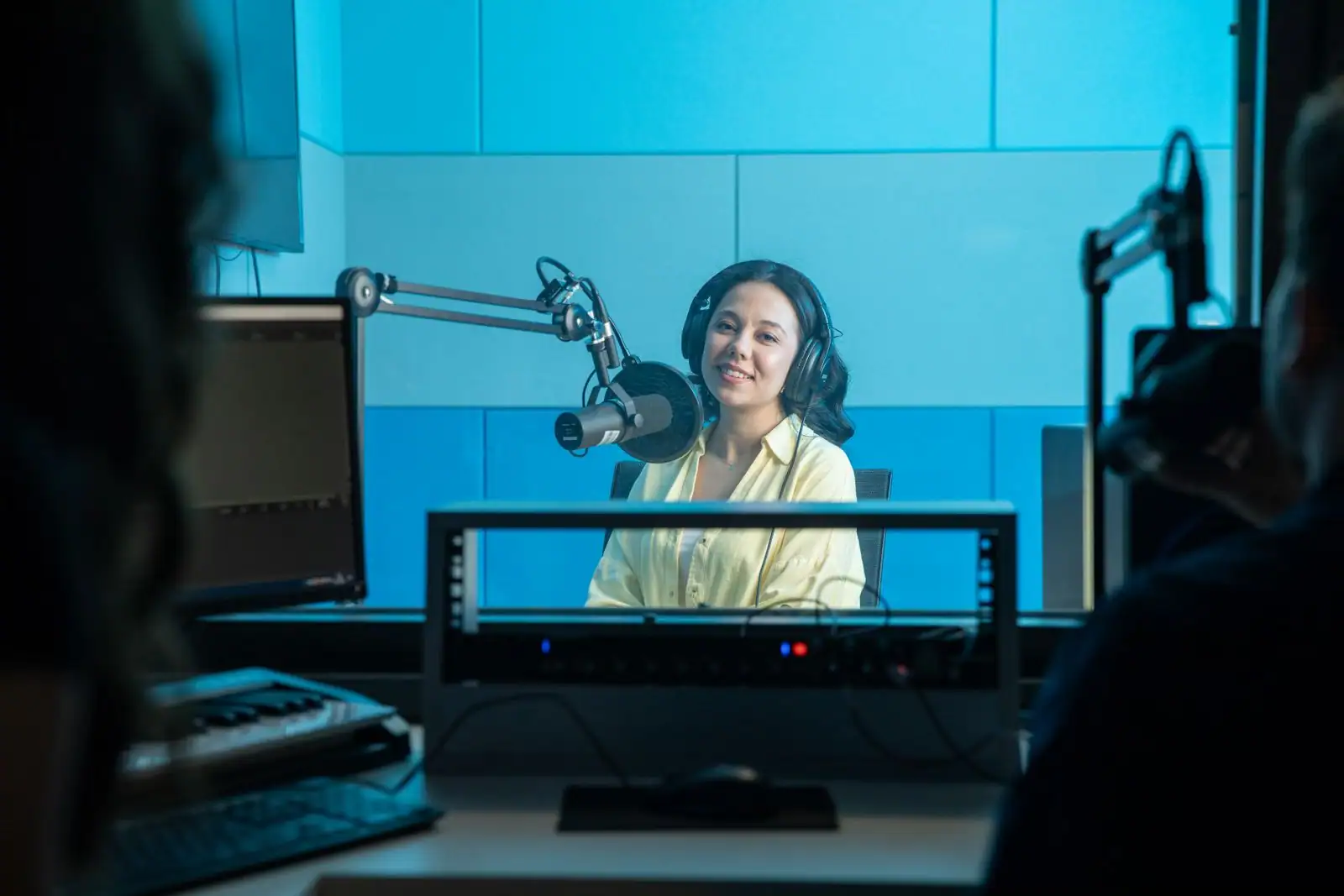 Animatrice au casque parlant devant un micro dans un studio de radio aux lumières bleues