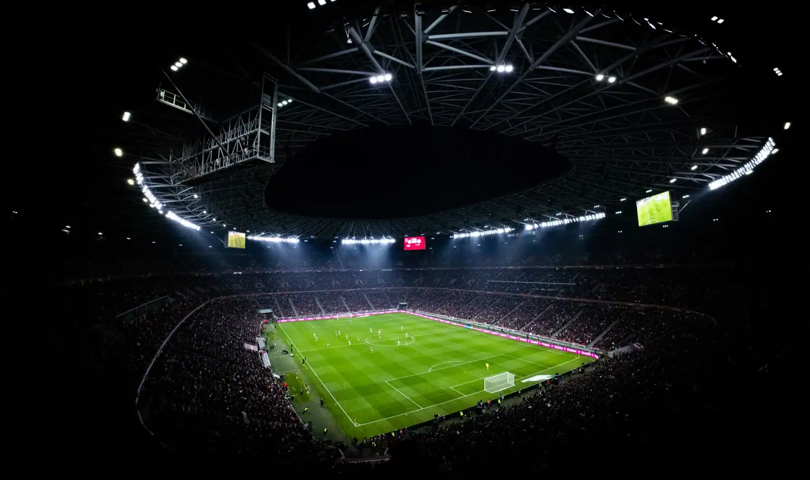 Stade de football comble illuminé par les projecteurs pendant un match de football en soirée