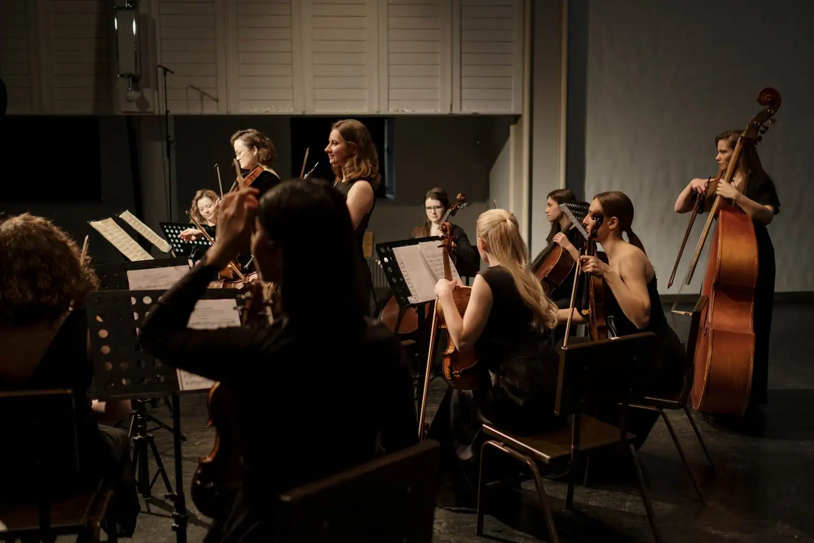 Ensemble de musique classique en concert sur scène, violonistes, violoncellistes et contrebassiste