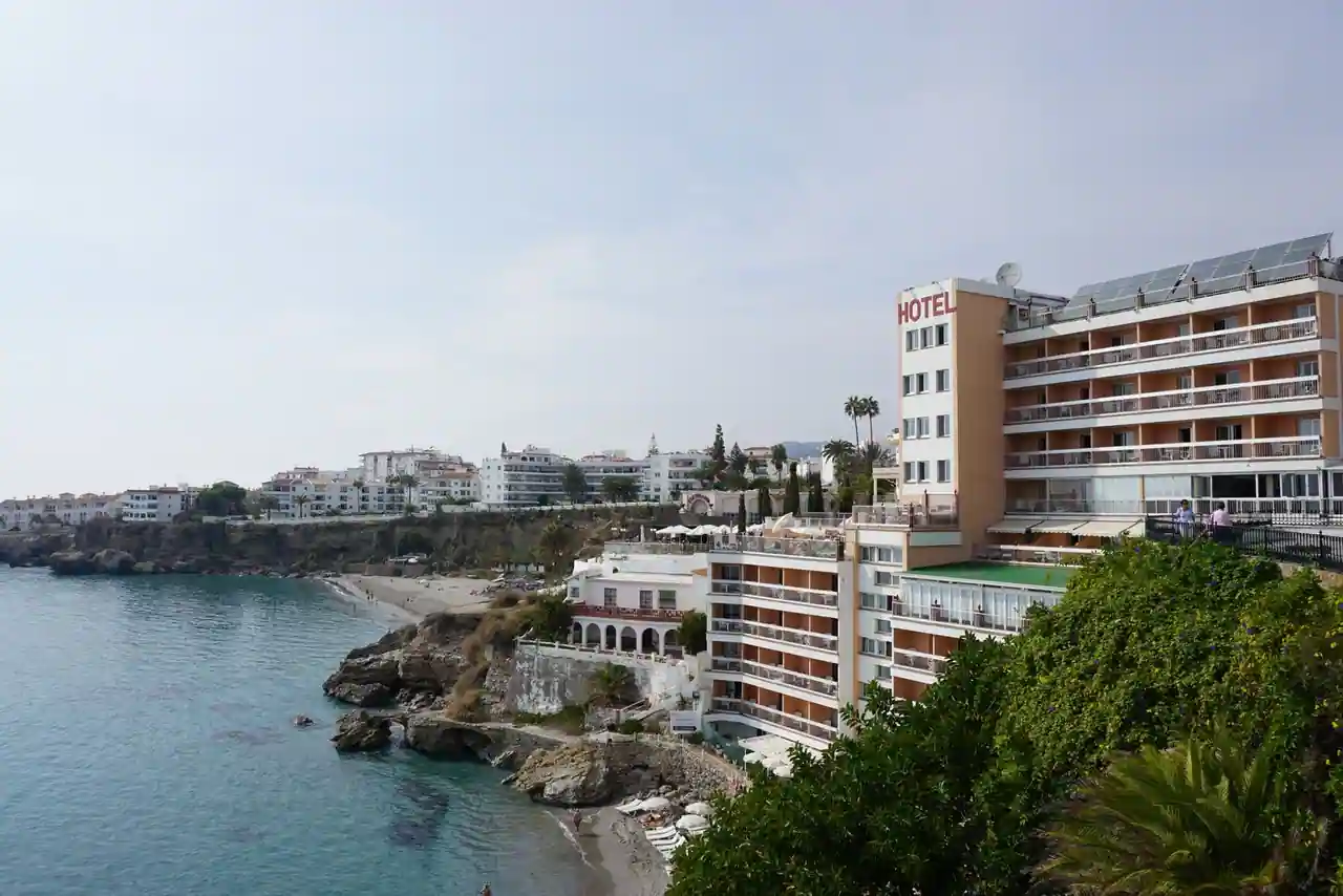 Façade d'un hôtel-resort méditerranéen sur la côte espagnole, avec terrasse et palmiers au soleil