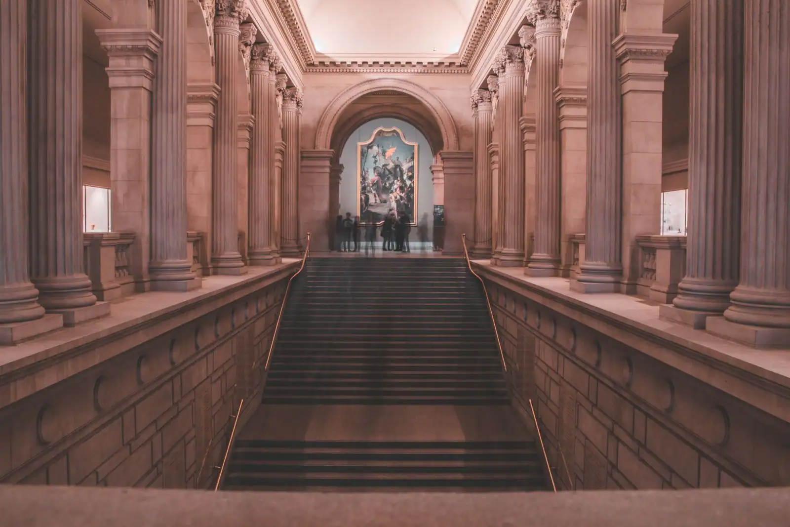 Grand escalier intérieur d'un musée classique bordé de colonnes, illustration d'une visite culturelle.