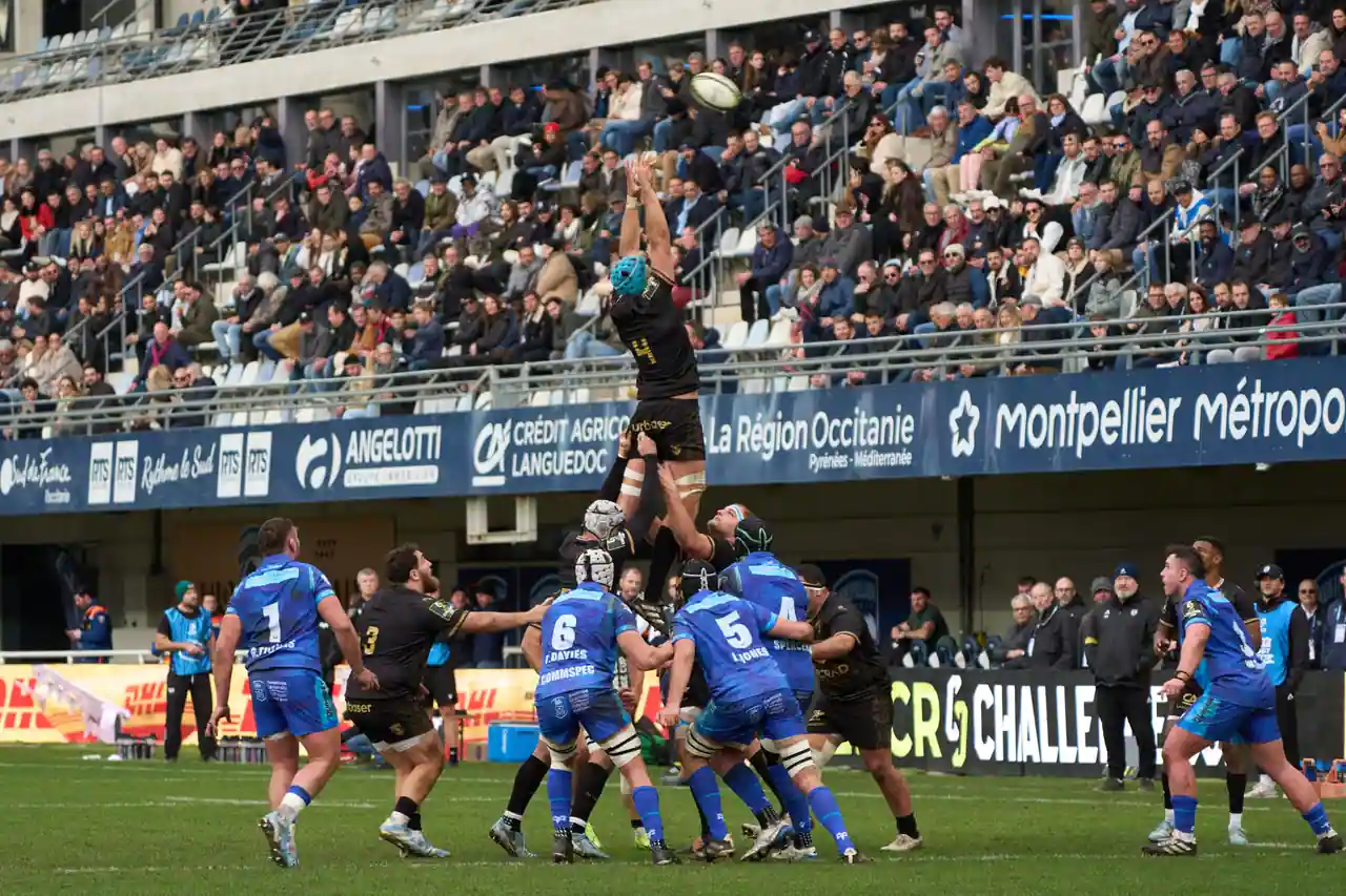 Touche lors d’un match de rugby dans un stade français, joueurs sautant pour capter le ballon ovale.