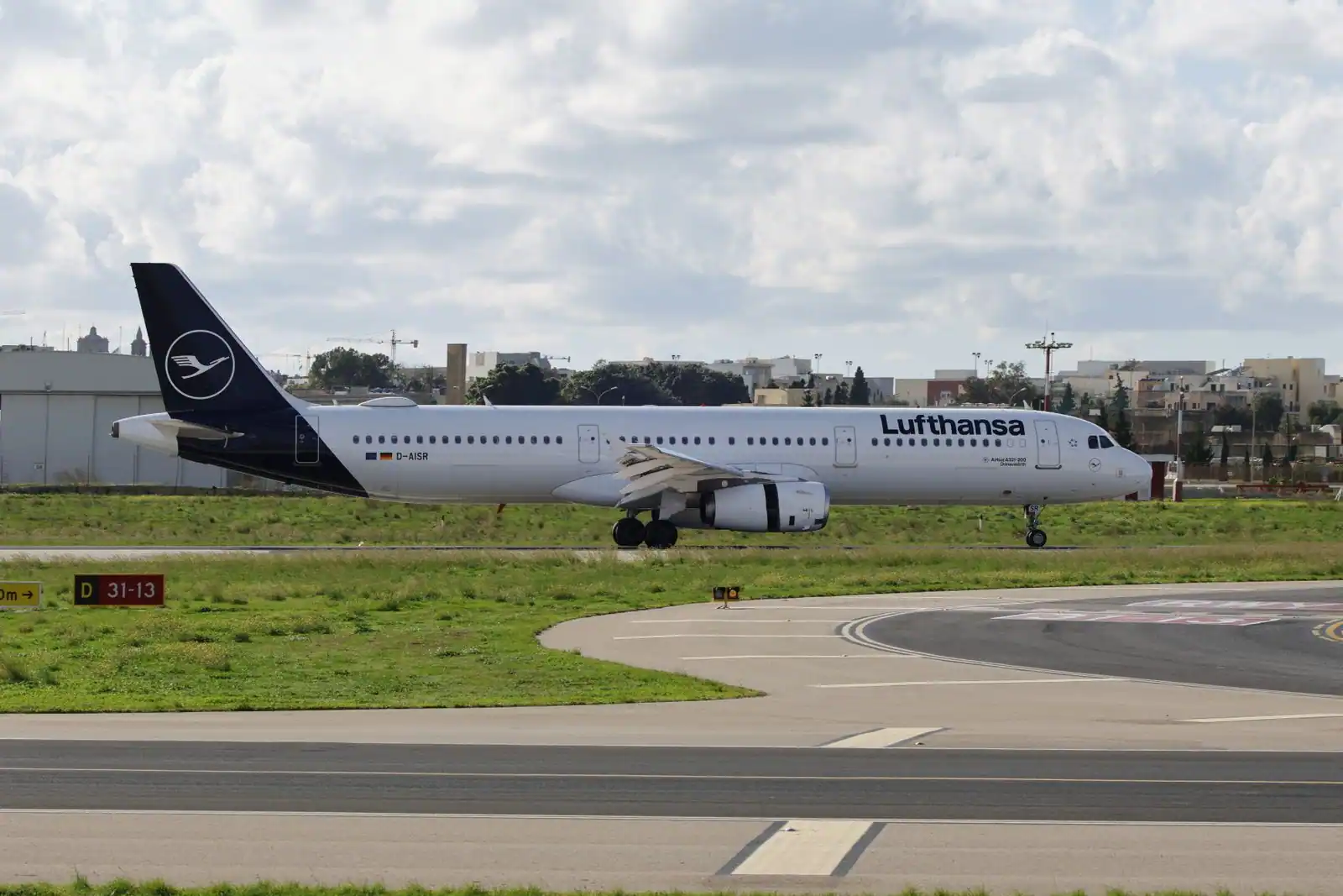 Un avion de ligne commercial roulant sur la piste d'un aéroport, sous un ciel nuageux.