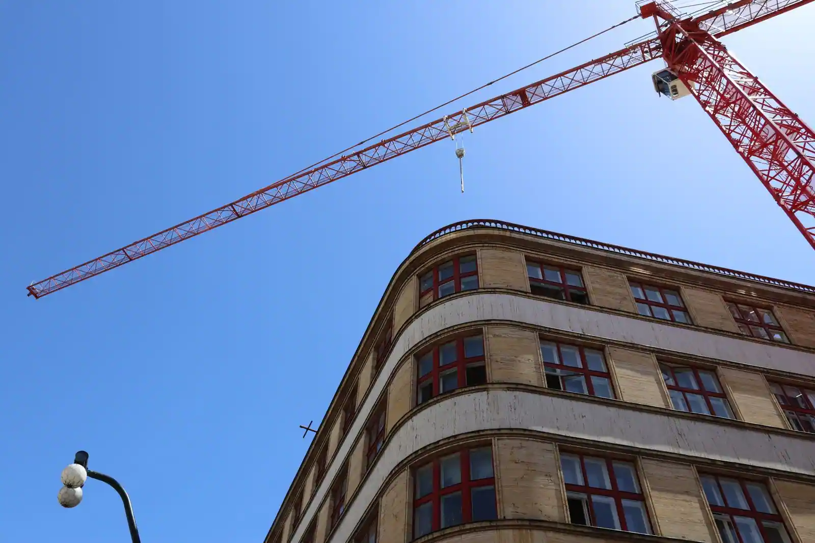 Grue de chantier rouge dressée au-dessus d'un immeuble sur un chantier de construction