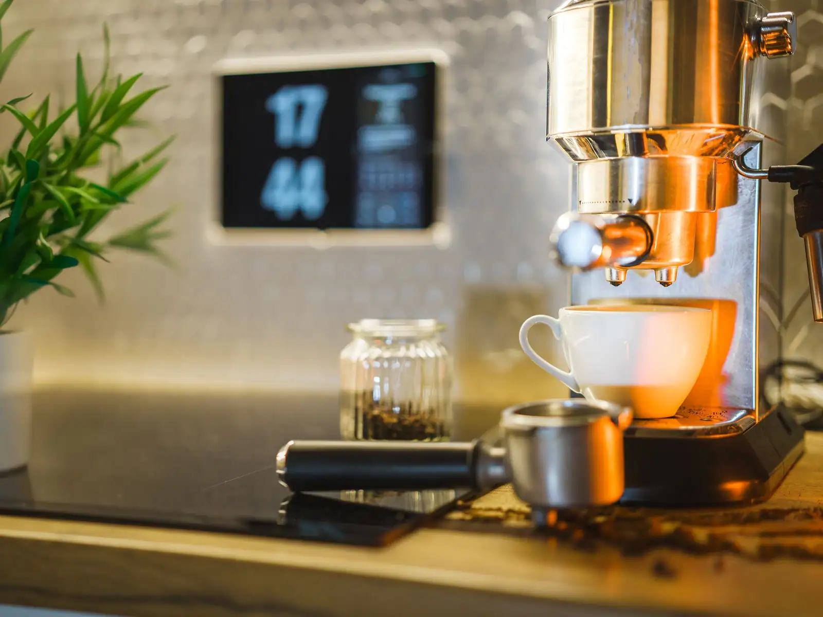 Machine à café expresso en inox sur un plan de travail de cuisine, avec une tasse et du café fraîchement moulu.