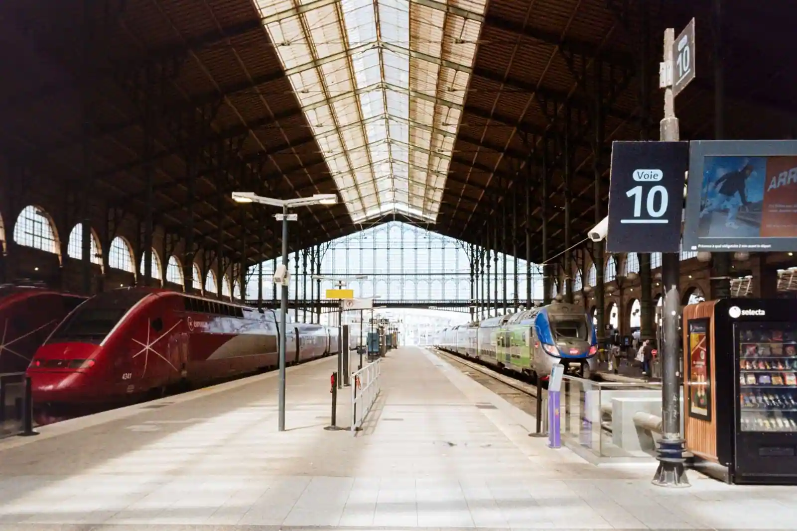 Quai de la gare du Nord à Paris, un train à grande vitesse rouge à gauche et un TER à droite.