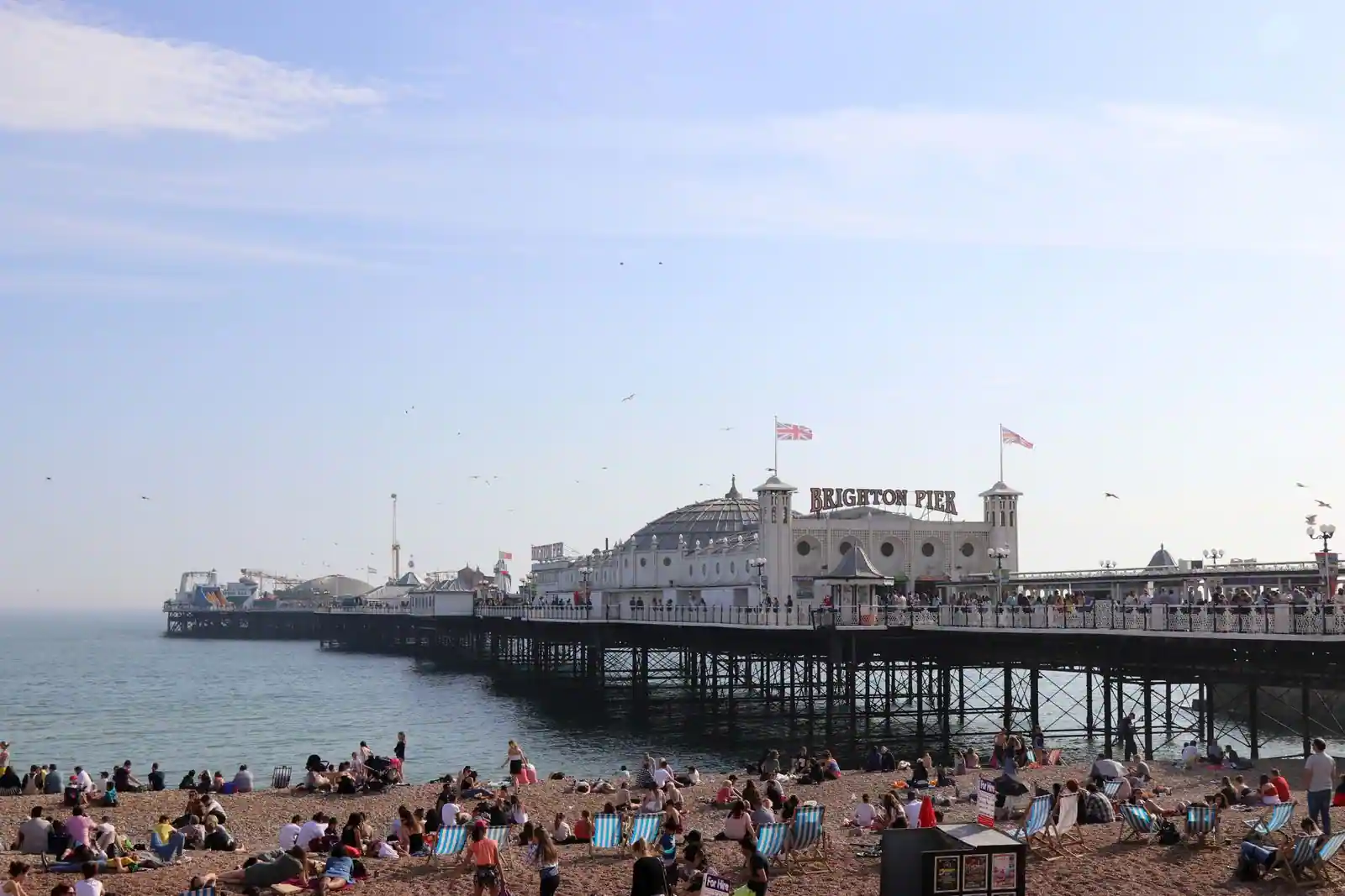 La jetée de Brighton et sa plage de galets couverte de transats rayés, un jour de forte affluence
