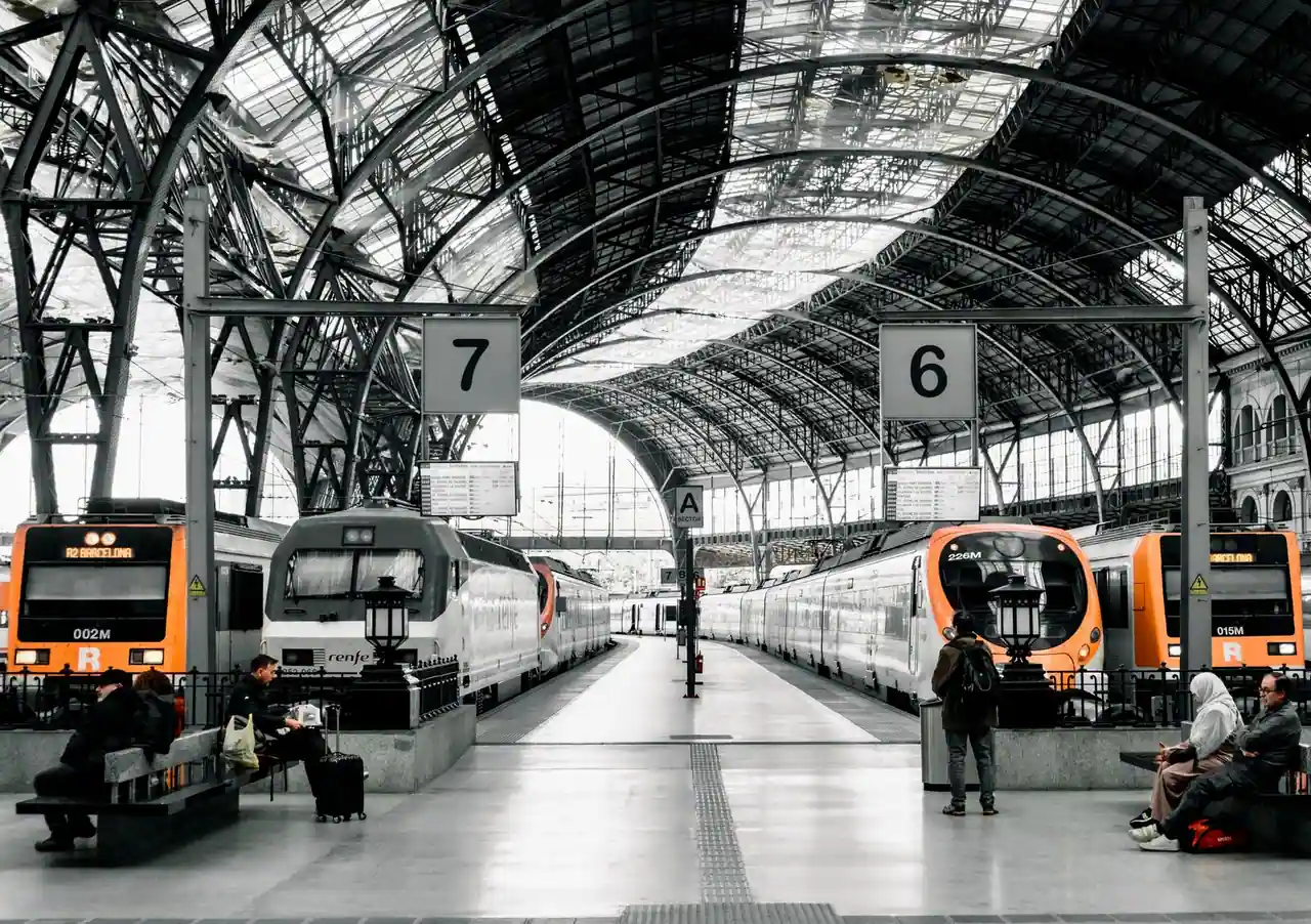 Trains Renfe à quai sous la verrière d'une gare de Barcelone, rames régionales et grandes lignes.