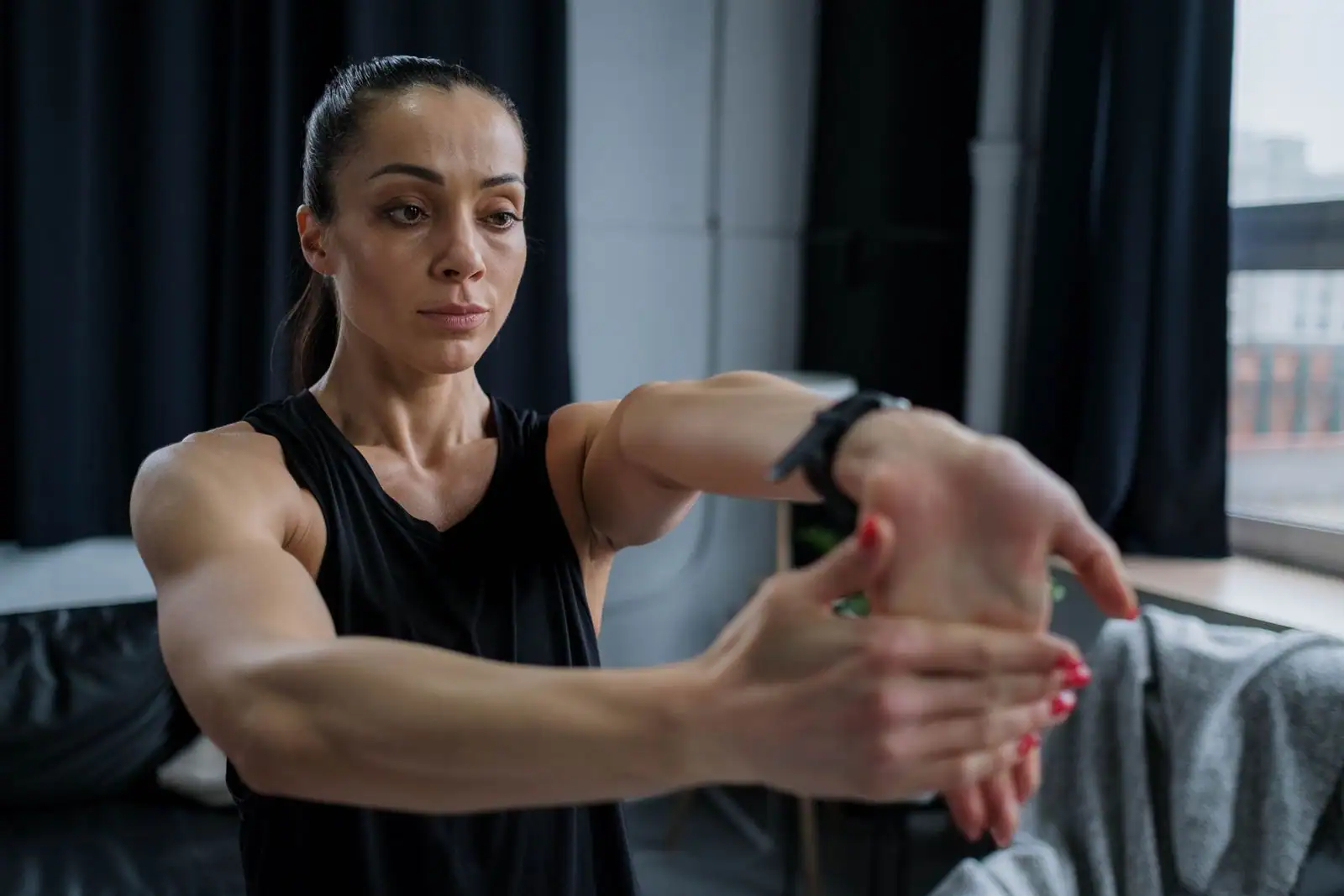 Femme en tenue de sport réalisant un étirement de fitness en intérieur, bras tendus devant elle