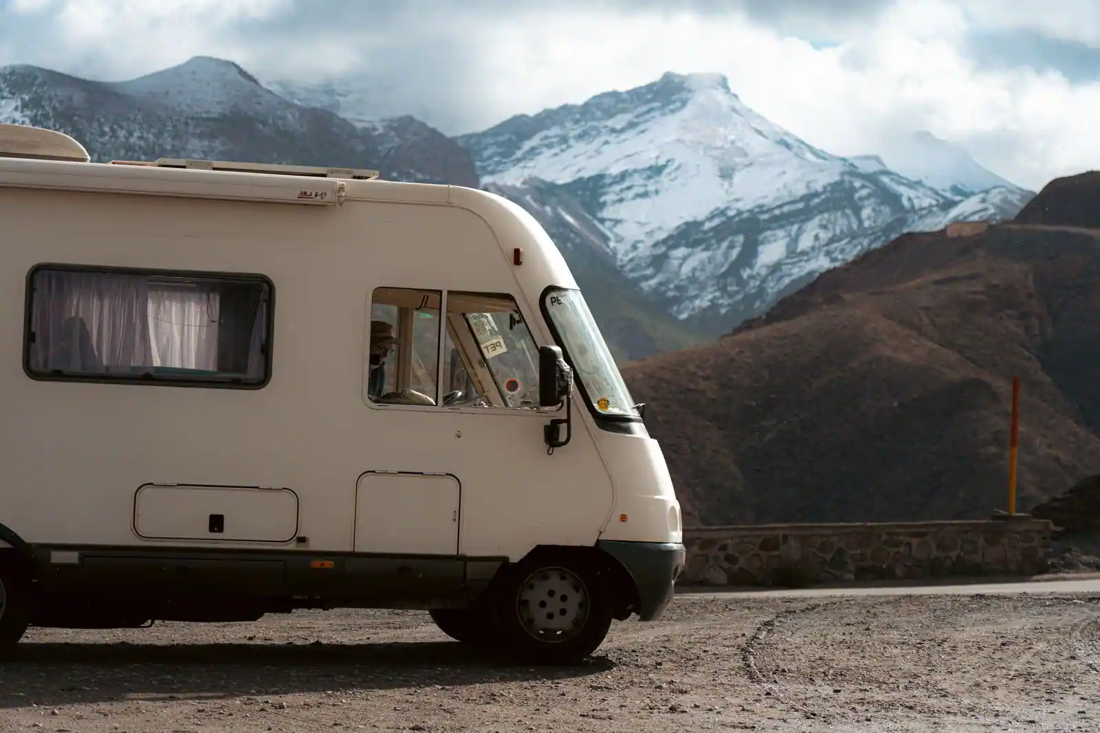 Camion aménagé stationné au bord d'une route de montagne en Europe, prêt pour un road-trip.